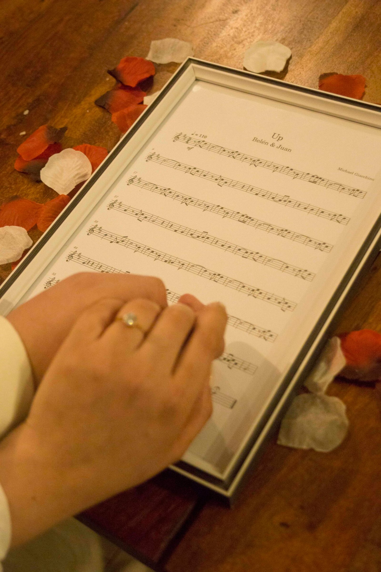 Manos con anillo sobre una partitura personalizada para Belén y Juan